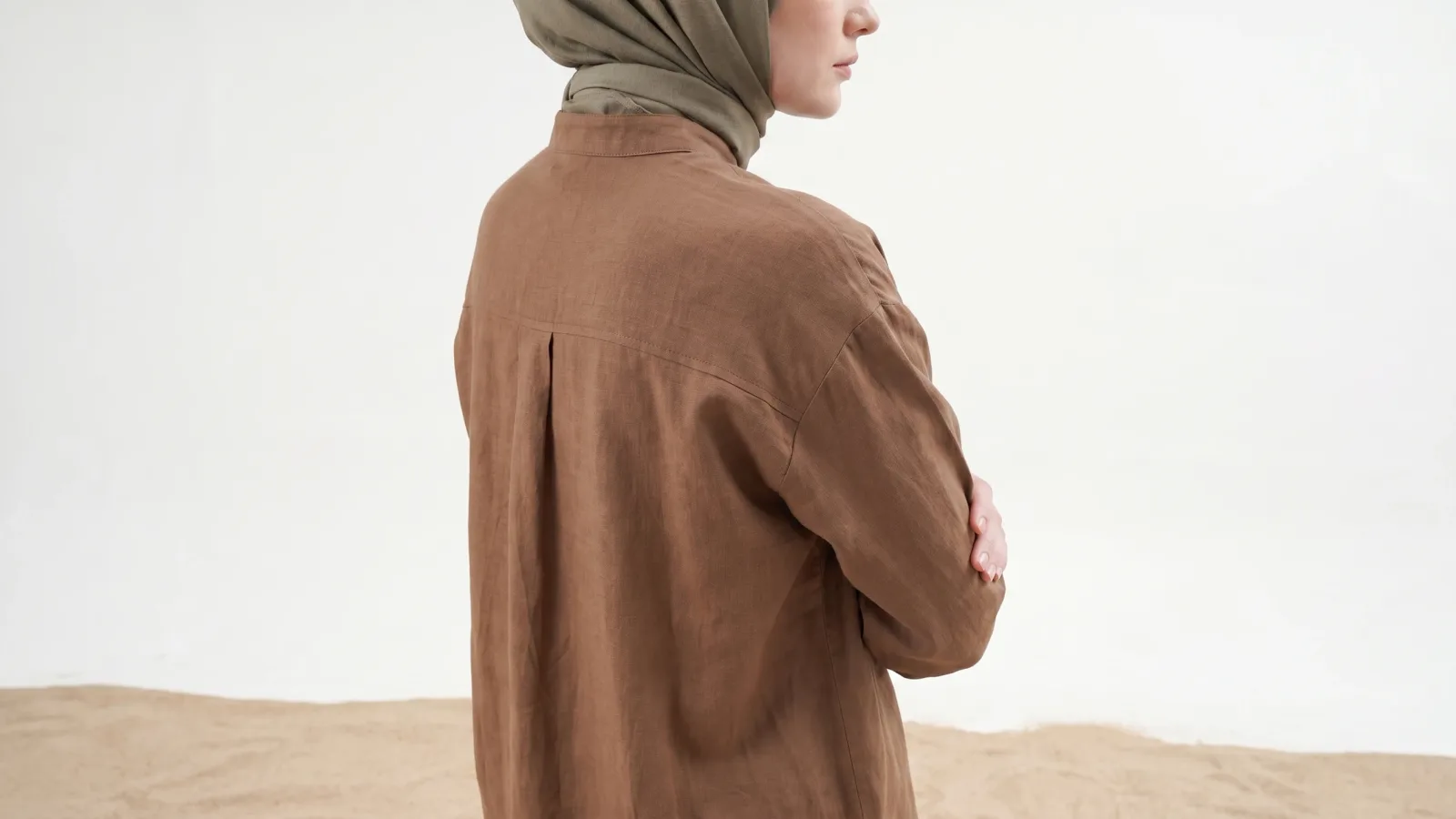 Back detail of a brown linen shirt on a virtual model with a khaki headscarf: scarf and fabric texture